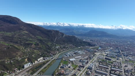European-scientific-centre-Grenoble-aerial-drone-view,-snowy-mountains-in-back